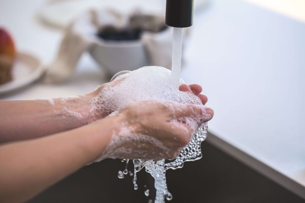 Pessoa lavando as mãos com sabonetes para hotel.