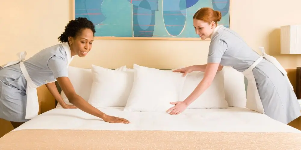 Duas camareiras arrumando uma cama de hotel