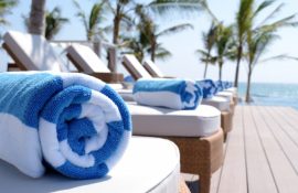 Toalha azul e branca em cima de cadeira de hotel do lado de uma piscina