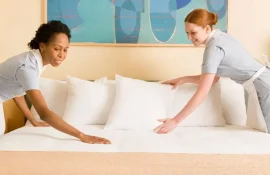 Duas camareiras arrumando uma cama de hotel